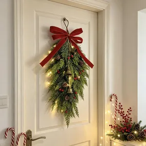 Beautiful Christmas teardrop swag with red bow and LED lights hanging on a door