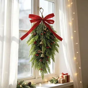 Close-up detail of a Christmas teardrop swag with a red bow, pinecones and bells