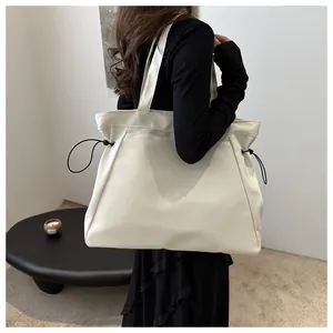 Side view of model wearing a large off-white canvas tote bag with drawstring detail