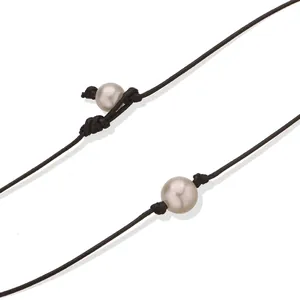 Detalle de una gargantilla minimalista de cordón negro con una perla de imitación blanca