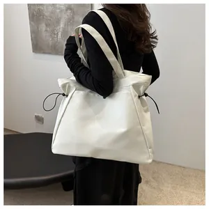 Close-up of minimalist large white tote bag with drawstring details worn by model