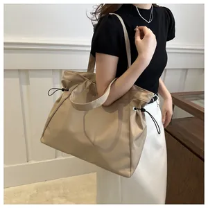 Close-up of large khaki canvas tote bag worn on shoulder by model