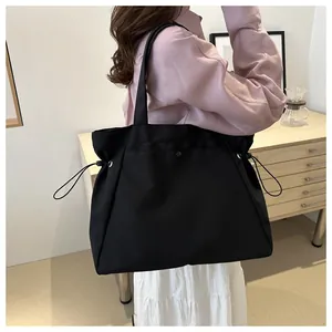 Black large capacity tote bag with side drawstrings shown in lifestyle commute setting