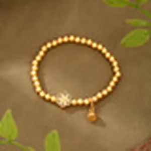 Close-up of an ancient gold beaded bracelet with a floral charm and bell accessory.