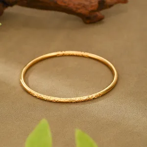 Close-up of traditional sand gold bangle with intricate relief texture detail