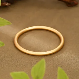 Close-up detail of ancient gold matte finish bangle with elegant textured background