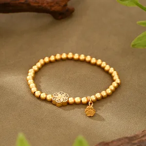 Detailed view of traditional matte gold beaded bracelet featuring a floral charm and Fu character