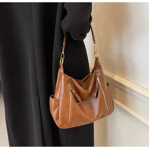 Detail view of a vintage brown leather hobo bag with gold zippers and side pockets