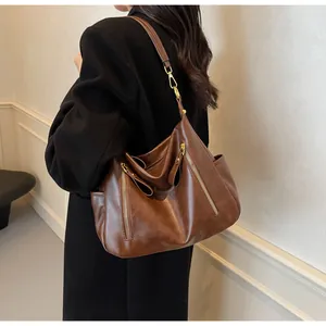 Large brown faux leather hobo tote bag shown worn on shoulder for size detail