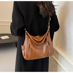 Detail of a large capacity retro brown faux leather tote bag worn as a shoulder bag