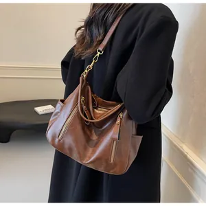 Close-up of brown vintage hobo bag on shoulder with gold zipper details