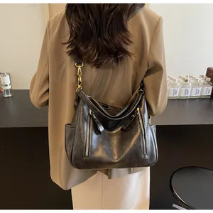 A detailed view of a large black retro leather tote bag being worn by a stylish model