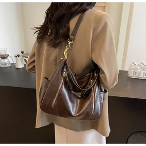 Stylish large retro brown leather hobo bag worn over shoulder in a modern cafe setting