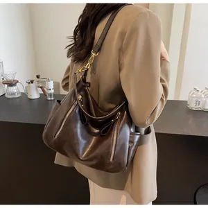 Detailed view of a vintage brown leather tote bag worn stylishly as an underarm shoulder bag