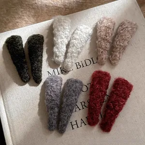 Set of fuzzy lambswool triangle hair clips in multiple autumn colors on a vintage book