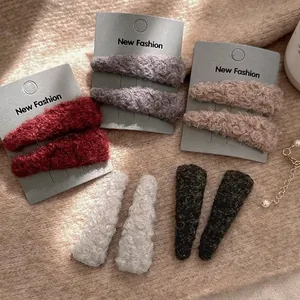 Detail view of triangular fuzzy lamb wool BB hair clips in red, grey, and beige for winter