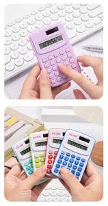 Detail showing multiple colorful mini pocket calculators held in hand on a white desk.