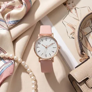Close-up of minimalist women's quartz watch with pink leather strap and textured white dial