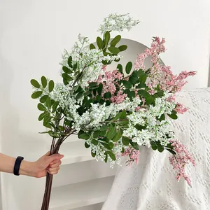 Nahaufnahme einer Hand, die einen üppigen Strauß weißer und rosa Kunstblumen hält