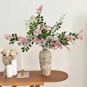 Elegante künstliche Sophora-Blumen in Rosa und Weiß in einer beigen strukturierten Vase