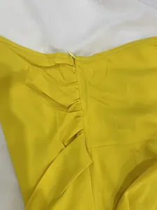 Close-up of bright yellow jumpsuit detail featuring stylish ruching and hidden zipper closure