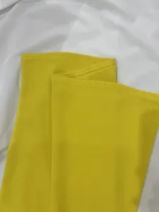 Close-up detail of high-quality stitching and fabric on yellow wide-leg jumpsuit