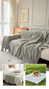 Vista detallada de una manta para sofá gris con diseño de espiga en varios escenarios.