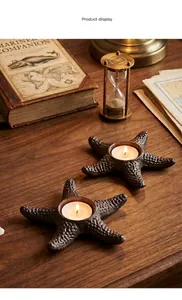 Detail view of two vintage cast iron starfish candle holders on a rustic wooden surface