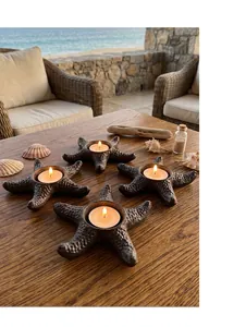 Rustic cast iron starfish candle holders on a wooden table with sea view background