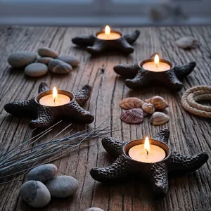 Decorative vintage cast iron starfish candle holders on rustic wooden table with pebbles