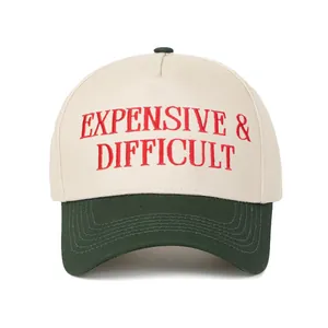 Λεπτομέρεια του κόκκινου κεντήματος 'Expensive & Difficult' σε κρεμ και πράσινο καπέλο