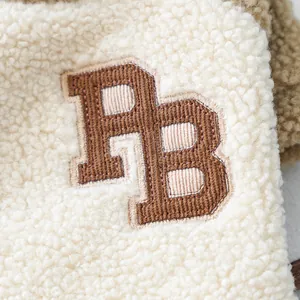 Close-up of PB embroidery on soft white sherpa fleece pet jacket.