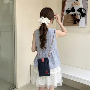 Back view of a model wearing a cute denim crossbody bag featuring cherry embroidery