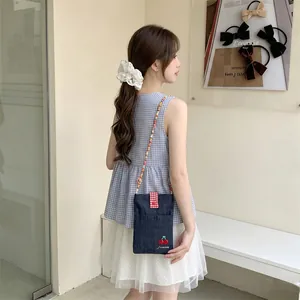 Detailed view of a cute denim crossbody bag with cherry embroidery worn by a model
