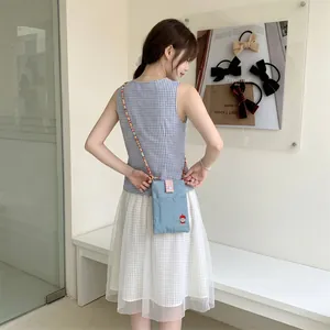 Cute blue denim crossbody bag featuring apple embroidery and colorful beaded strap on model