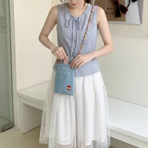 Detail of cute denim crossbody bag with apple embroidery and beaded strap