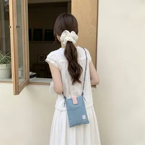 Detail of cute denim crossbody bag with rabbit embroidery and colorful rope strap