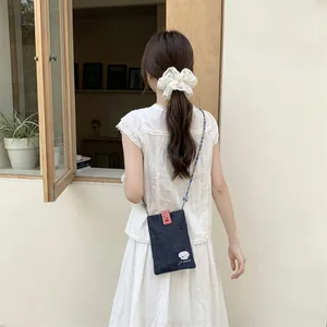 Rear view of a model wearing a cute embroidered denim small crossbody bag outdoors