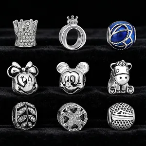 Nahaufnahme verschiedener silberfarbener Charms, darunter Mickey Mouse, Krone und Einhorn