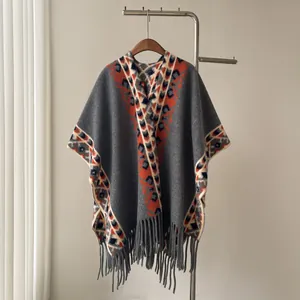 Poncho gris en cachemire d'imitation avec motifs orange et franges décoratives.