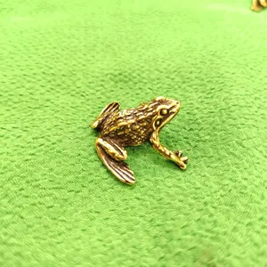 Vue macro détaillée d'une figurine de grenouille en laiton massif vintage sur tissu vert