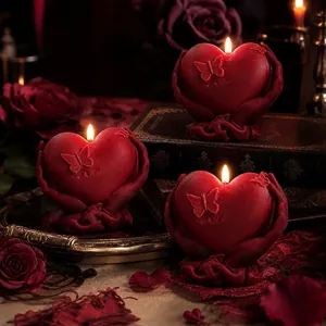 Detailed red heart-shaped candles held by hands with butterfly accents in a romantic setup