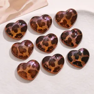 Detail van hartvormige acryl patches met glitter luipaardprint voor DIY sieraden maken.