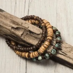 Dettaglio di bracciali a più strati con perline di legno e pietra verde su legno.