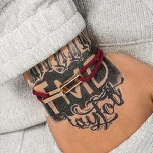 Primo piano di braccialetti intrecciati bordeaux con connettori in metallo dorato