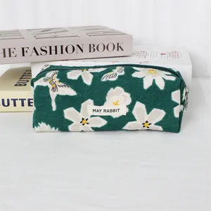 Close-up of green corduroy pencil case with white floral print and MAY RABBIT label
