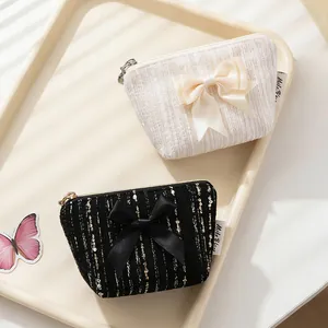 Elegantes monederos de tweed con lazo en blanco y negro sobre una bandeja minimalista
