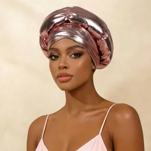 Close-up of metallic rose gold turban hat showing detailed pleats and crossover design.