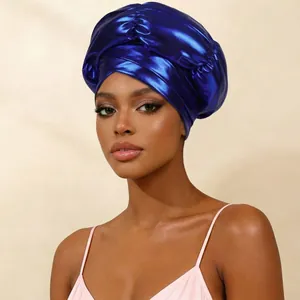 Detail view of electric blue metallic turban hat with elegant front cross design.