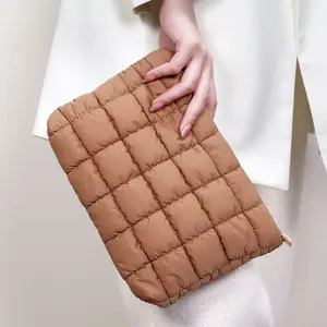 Trousse à maquillage marron matelassée tenue comme une pochette mode pour femme.